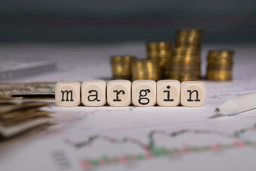 six small wooden cubes representing margin requirements concept, are placed in the background of currency, stock trends, etc.