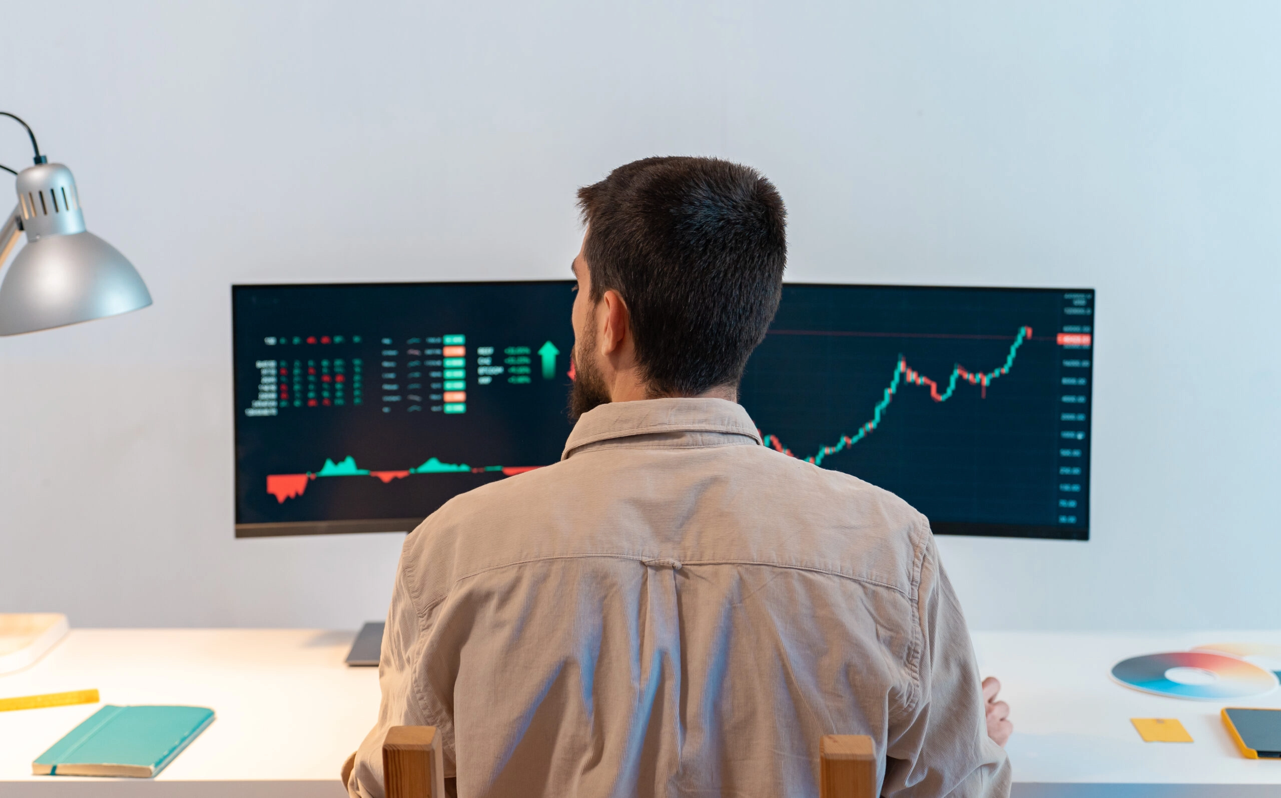 day trader in front of two trading desktop app screens