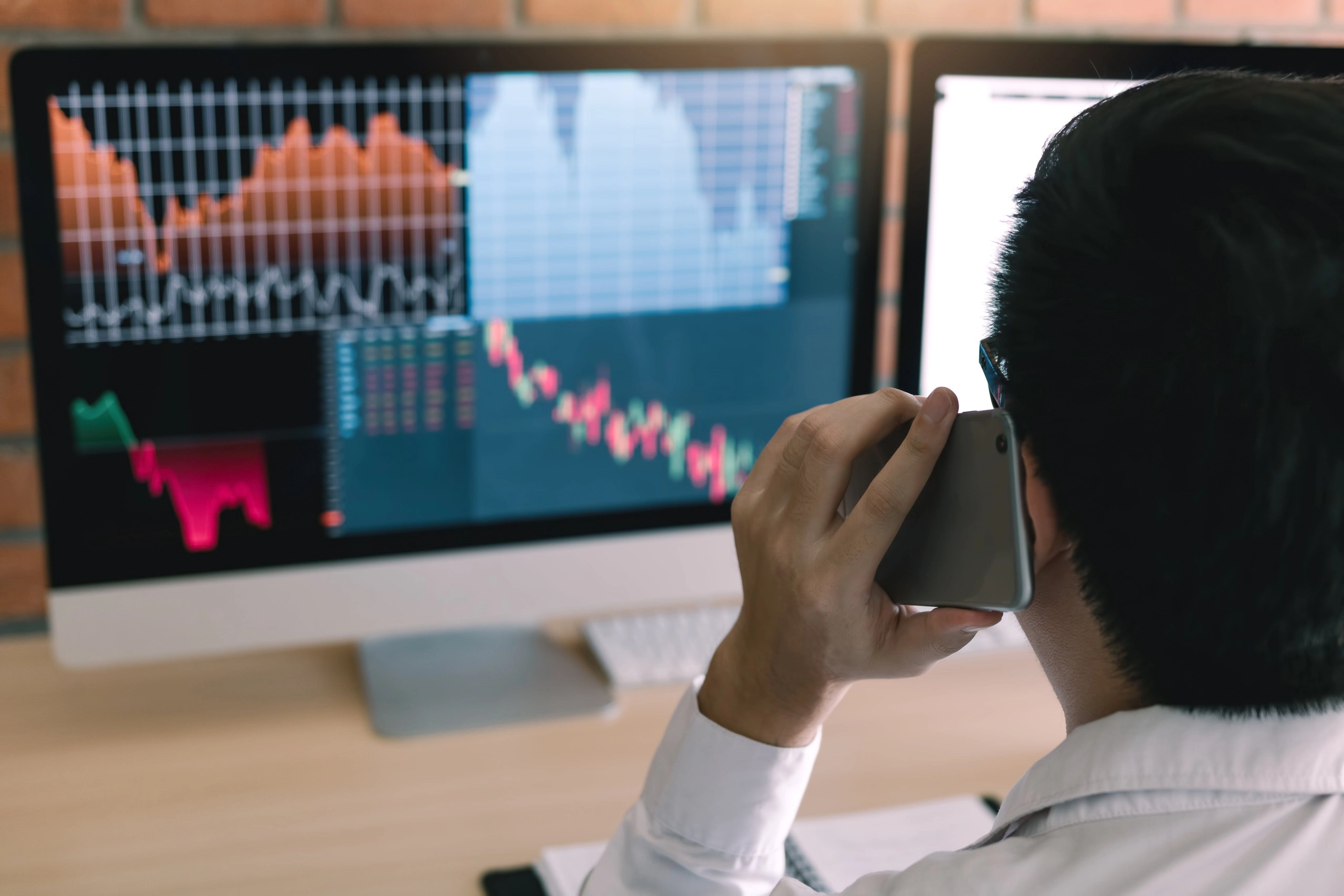 trader checking stock market graph for trading while being on the phone